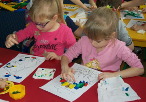 Olga i Inga malują dinozaury farbami.