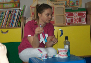 Pani Paulina pokazuje elektryczną szczoteczkę do zębów.