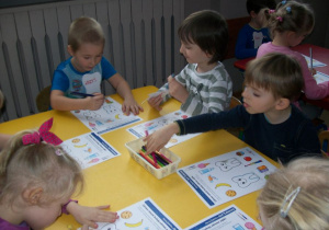 Uśmiechnięty i smutny ząb - dzieci przy żółtym stoliku przyporządkowują elementy.