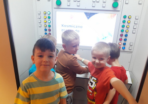 Chłopcy przed symulatorem lotu w kosmos.