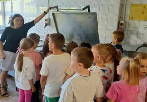 Dzieci oglądają wielka patelnie na której w kuchni panie przygotowują pyszne placuszki.