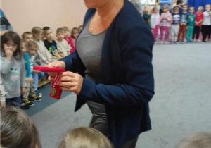 Pani Małgosia pokazuje dzieciom medal.