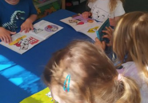 Przedszkolaki oglądają książeczki, które przyniosły z domowych biblioteczek.