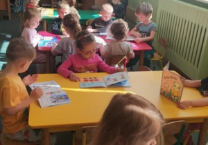 Przedszkolaki oglądają książeczki.