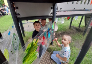 Chłopcy malują obrazki na folii.