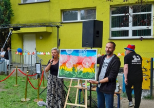 Pani Dyrektor i zadowolony rodzic prezentują zakupiony obraz