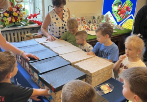 Dzieci odgadują warzywa i owoce znajdujące się w zakrytych pudełkach.