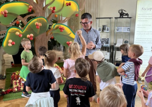 Dzieci zwiedzają salę z wystawą jabłek.