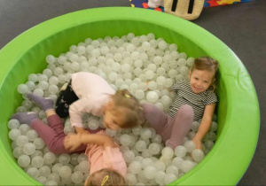Uśmiechnięte dziewczynki bawią się w basenie z kulkami.