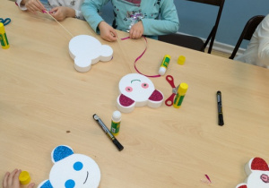 dzieci przyklejają elementy misia