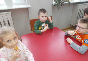 Zuzia, Oskar i Julek zajadają pączki.