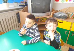 Wojtek i Tomek z wielkim apetytem zjadają pączki.