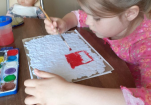 Zuzia maluje rysunek na papierze czerpanym.