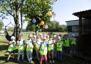 Dzieci na działce przywitało drzewo z balonami.