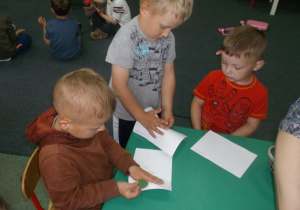 Dzieci odbijają na kartce ręce pomalowane farbami.