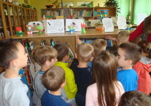 dzieci oglądają książki, które stoją na regale