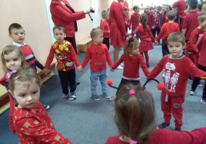 Dzieci w czerwonych strojach tańczą w kole.