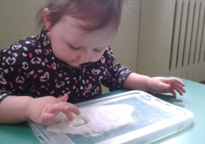 Dziewczynka rysuje w soli.