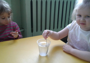 Dziewczynka miesza sól w wodzie , aby się rozpuściła.