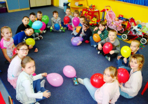 przedszkolaki trzymają swoje balony siedząc w kole