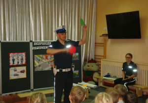 policjant prezentuje czerwony i zielony krążek