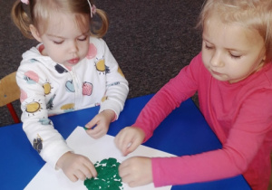 Julia i Pola wyklejają kropkę zieloną plasteliną.