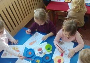Dziewczynki malują farbami liść kasztanowca.