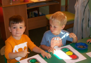 Hubert i Maciuś malują zieloną farbą światło sygnalizatora.