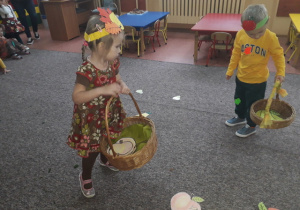 Dzieci zbierają owoce do koszyków.