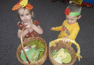 Kaja i Nikodem prezentują w koszykach swoje zbiory owoców.