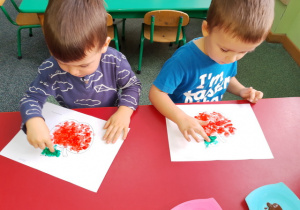 Hubert i Mateusz malują paluszkami jabłko.