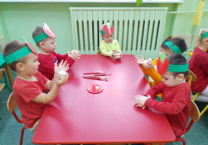 Chłopcy przy stoliku czerwonym formują jabłuszka z masy solnej.