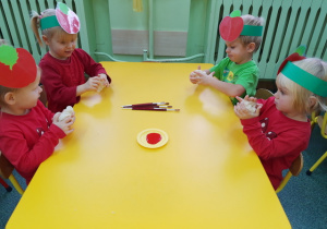 Dzieci przy stoliku formują jabłuszka z masy solnej.
