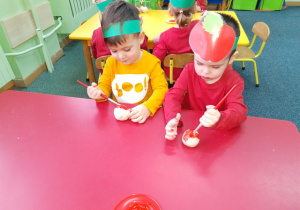 Hubert i Miłosz malują swoje jabłuszko czerwona farbą.