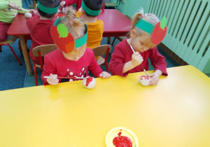 Lilianka i Łucja malują swoje jabłuszko czerwona farbą.