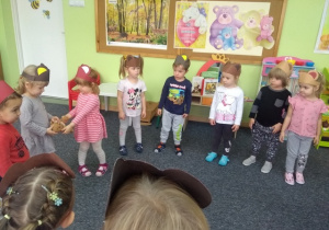 Dzieci w kole przy muzyce bawią się z misiem.