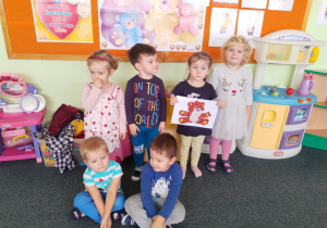 Dzieci prezentują swojego wyklejonego misia brązowymi kuleczkami.