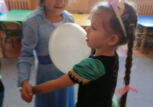Dziewczynki tańczą z balonem.