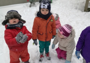 Dzieci lepią kule śniegowe.