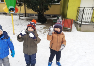 Chłopcy prezentują ulepione kule sniegowe.