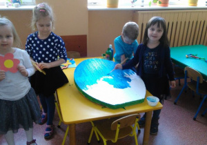 Dziewczynki malują jajko na niebiesko.