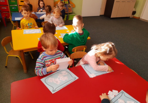 Dzieci przy stoliku czerwonym układają elementy pogody.