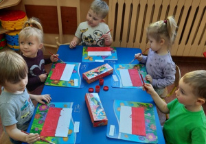 Przedszkolaki malują farbami biało-czerwoną flagę Polski.
