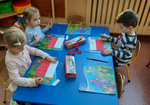 Julia, Pola i Bartek malują farbami flagę Polski.