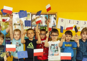 Dzieci machają flagami Polski i Unii Europejskiej.