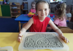 Dziewczynka rysuje na piasku.