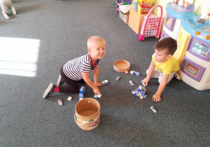 Pawełek i Hubert bawią się klockami na dywanie.