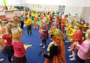 Przedszkolaki tańczą trzymając kolorowe liście.