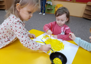 Stella i Ola żółtą farbą malują słoneczko.