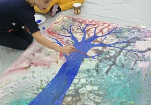 Dziewczynka maluje drzewo drzewo.